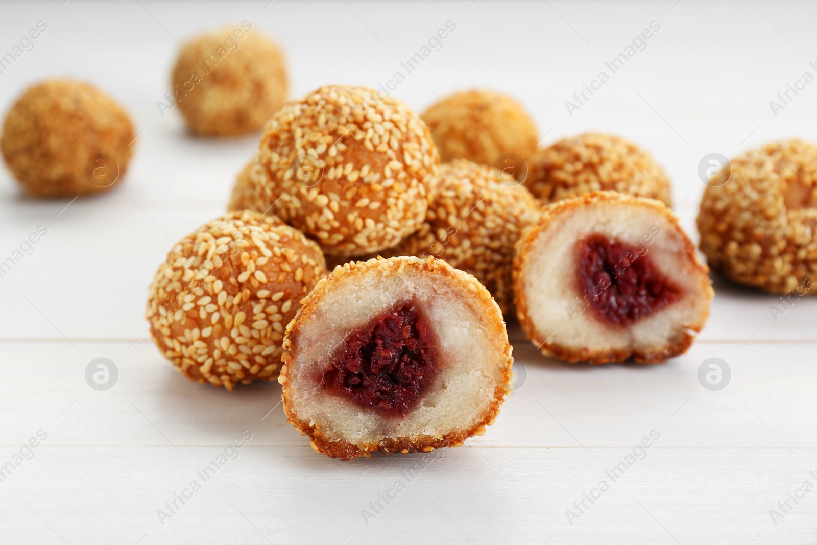 Photo of Delicious sesame balls with red bean paste on white wooden table, closeup