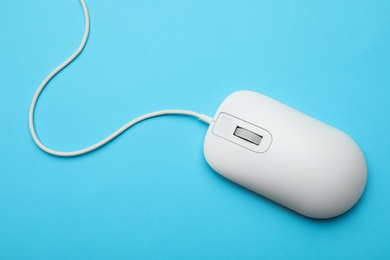 Wired computer mouse on light blue background, top view