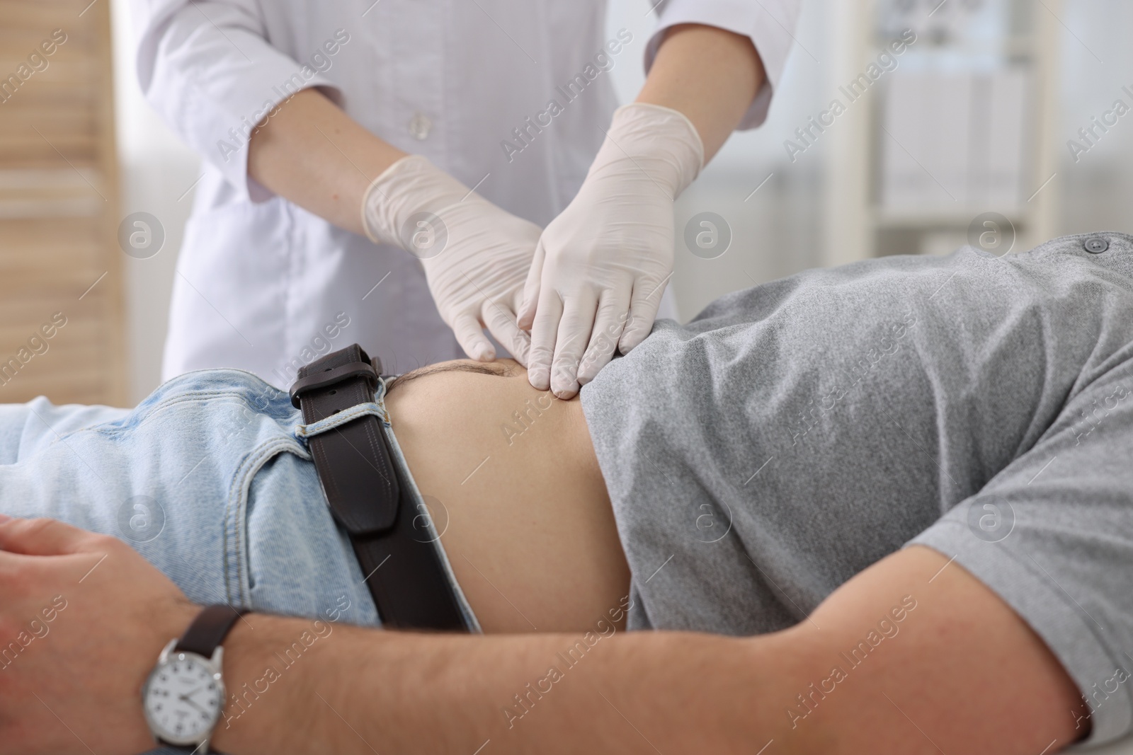 Photo of Gastroenterologist examining patient with stomach pain in clinic, closeup