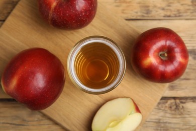 Photo of Glass of delicious cider and ripe red apples on wooden table, flat lay