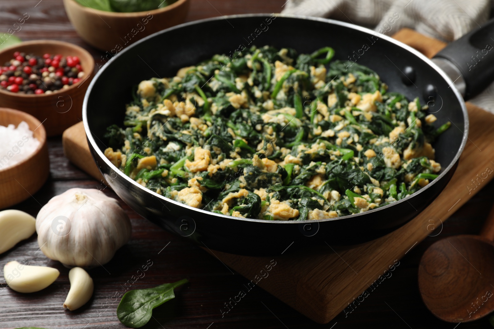 Photo of Tasty spinach dip with eggs in dish served on wooden table, closeup