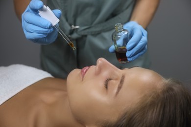 Photo of Cosmetologist applying serum on client's face in salon