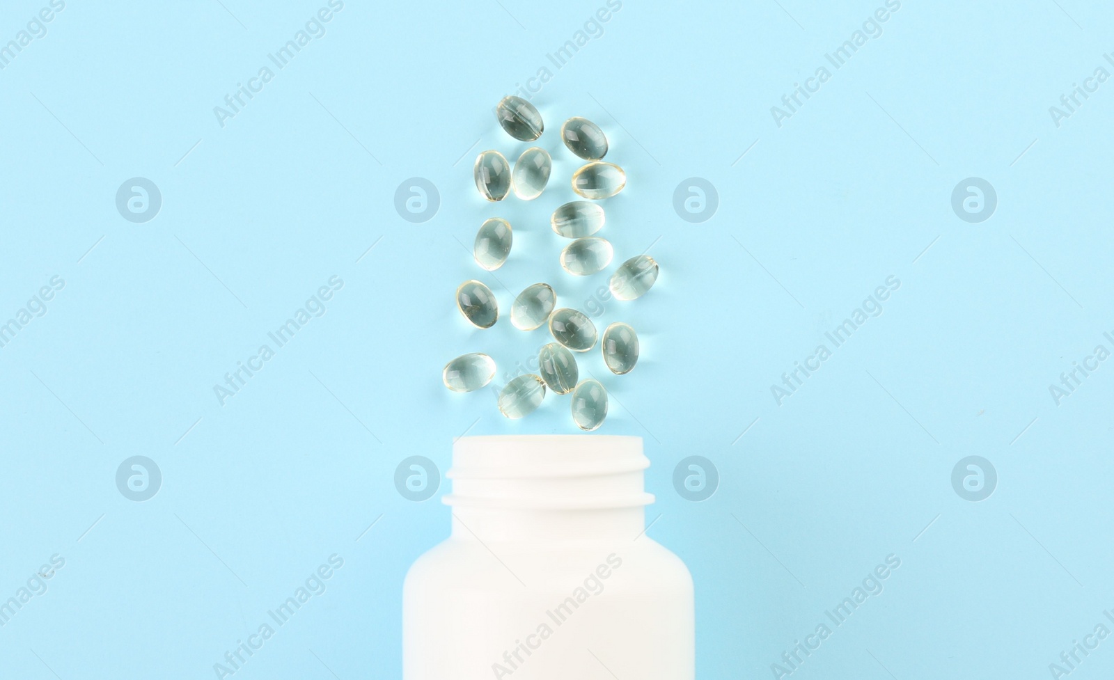 Photo of Bottle and vitamin capsules on light blue background, top view