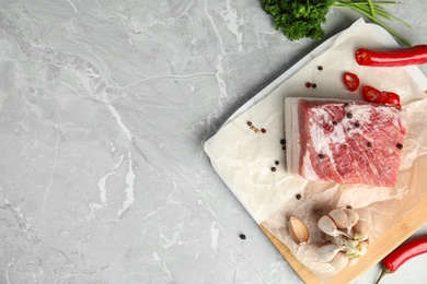 Photo of Flat lay composition with pork fatback and spices on grey table, top view. Space for text