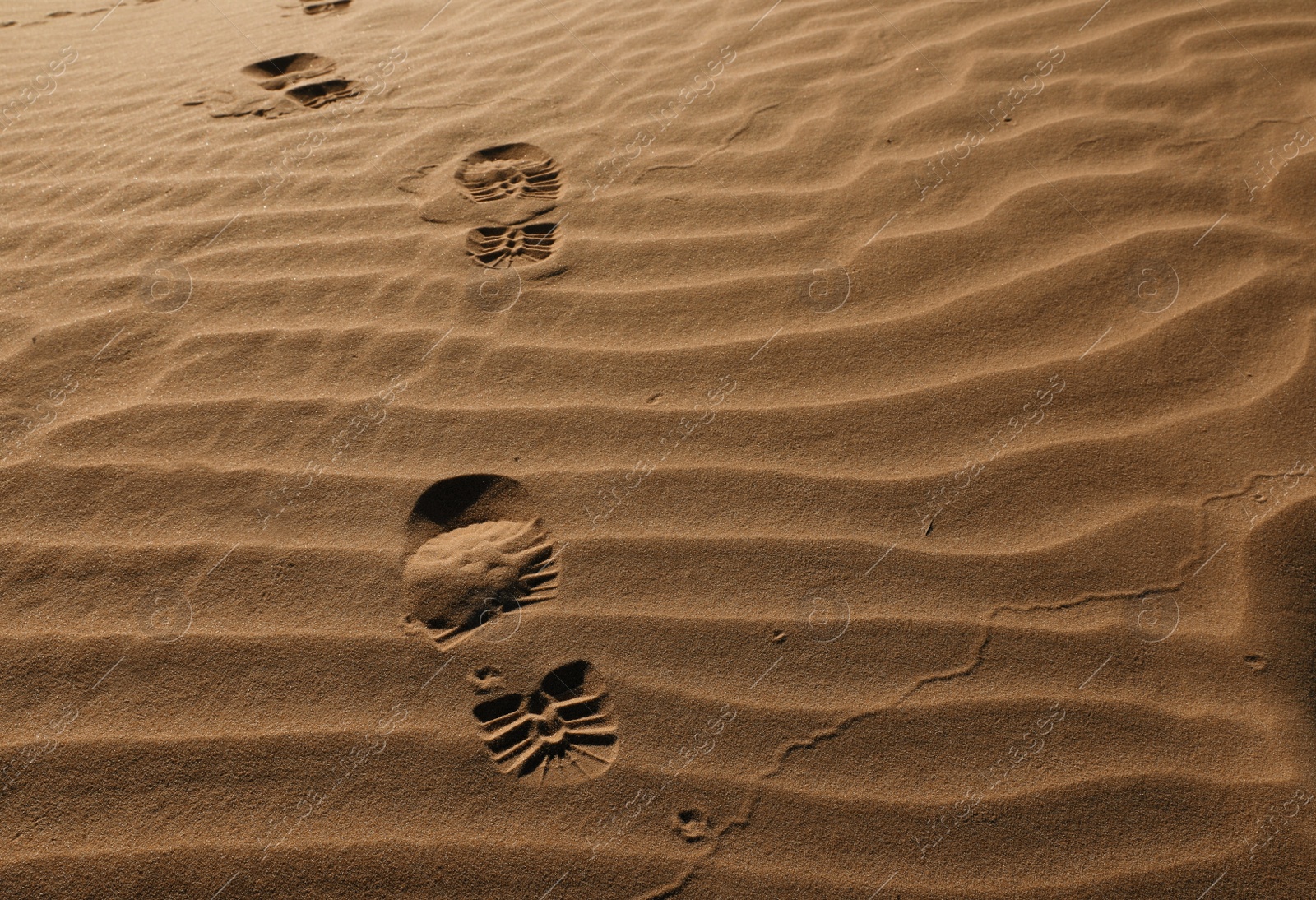 Photo of Trail of footprints on sand in desert