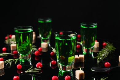 Absinthe in shot glasses, cranberries, rosemary and brown sugar on mirror table. Alcoholic drink