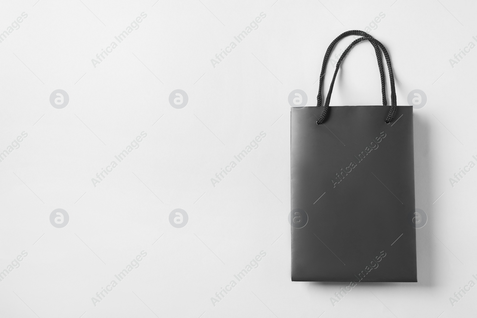 Photo of Black paper bag on light grey background, top view. Space for text