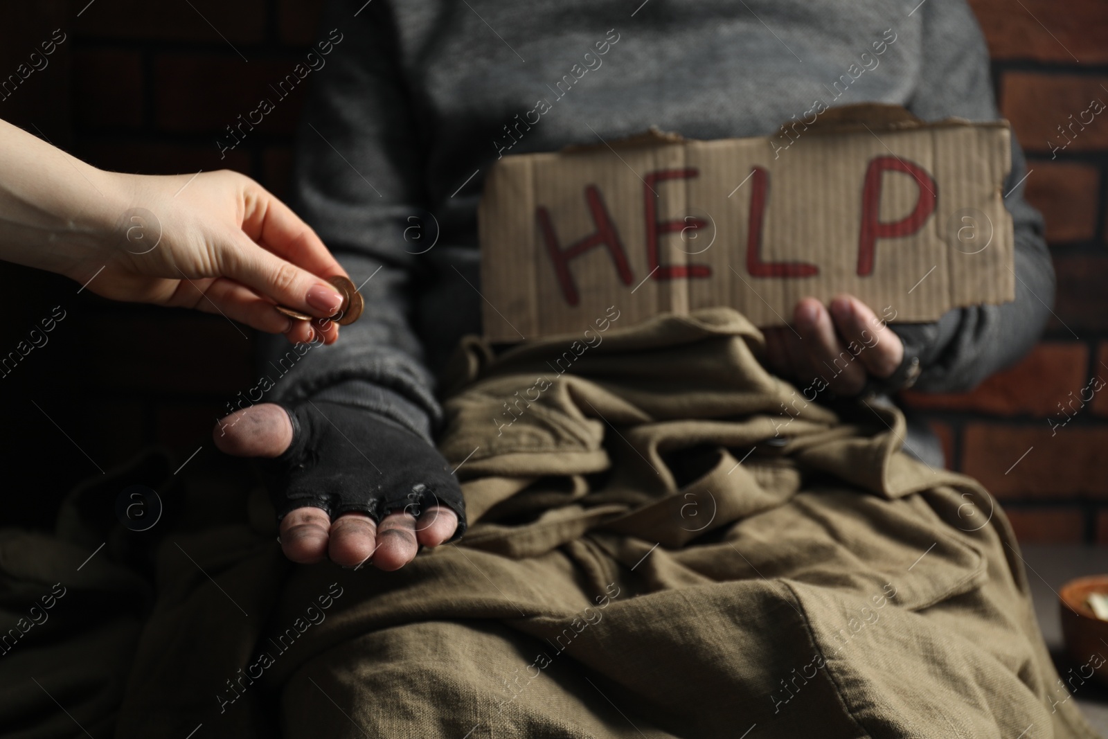 Photo of Woman giving coins to poor homeless man with help sign, closeup. Charity and donation