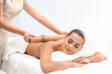 Young woman having massage with bamboo stick in wellness center