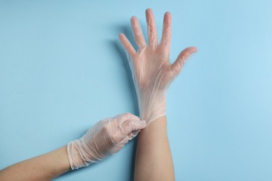 Photo of Doctor wearing medical gloves on light blue background, top view