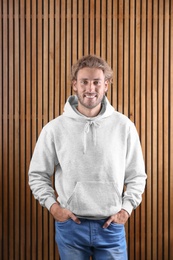 Photo of Portrait of man in hoodie sweater on wooden background. Space for design