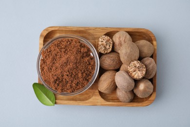 Photo of Nutmeg powder, seeds and green leaf on white background, top view
