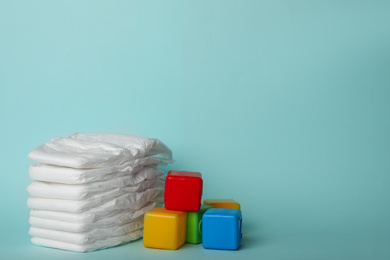 Photo of Diapers and plastic cubes on light blue background. Space for text
