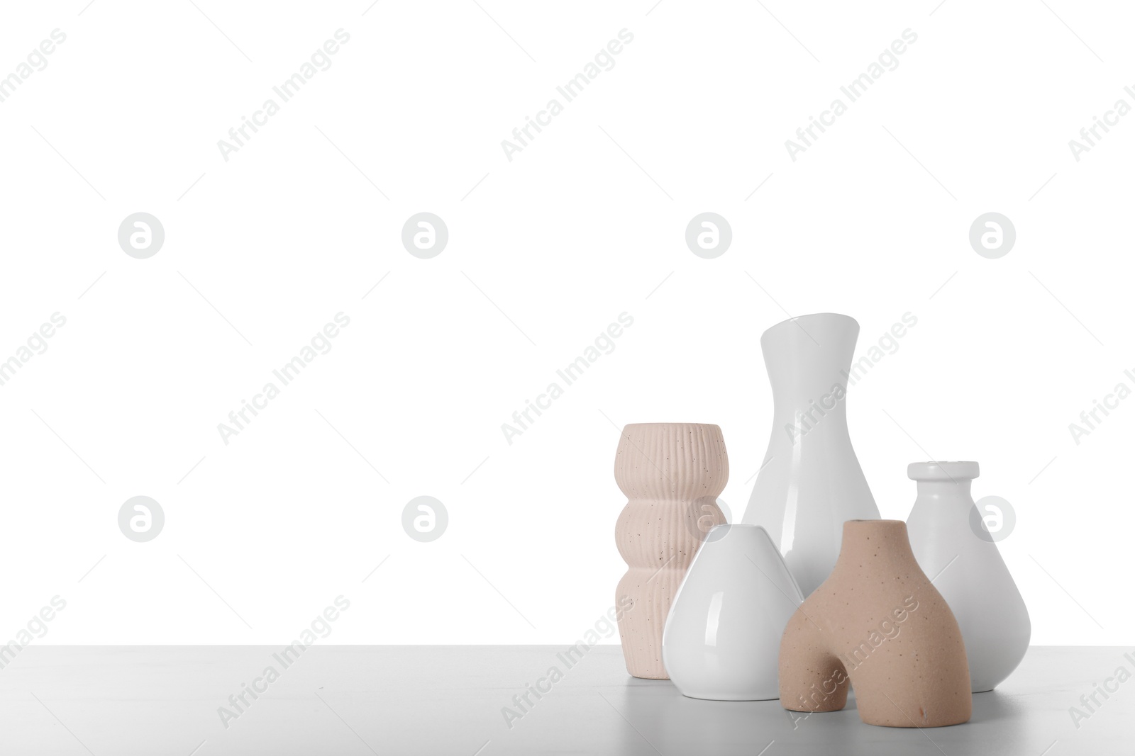 Photo of Different stylish vases and dried flowers on light table against white background, space for text