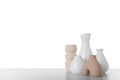 Photo of Different stylish vases and dried flowers on light table against white background, space for text