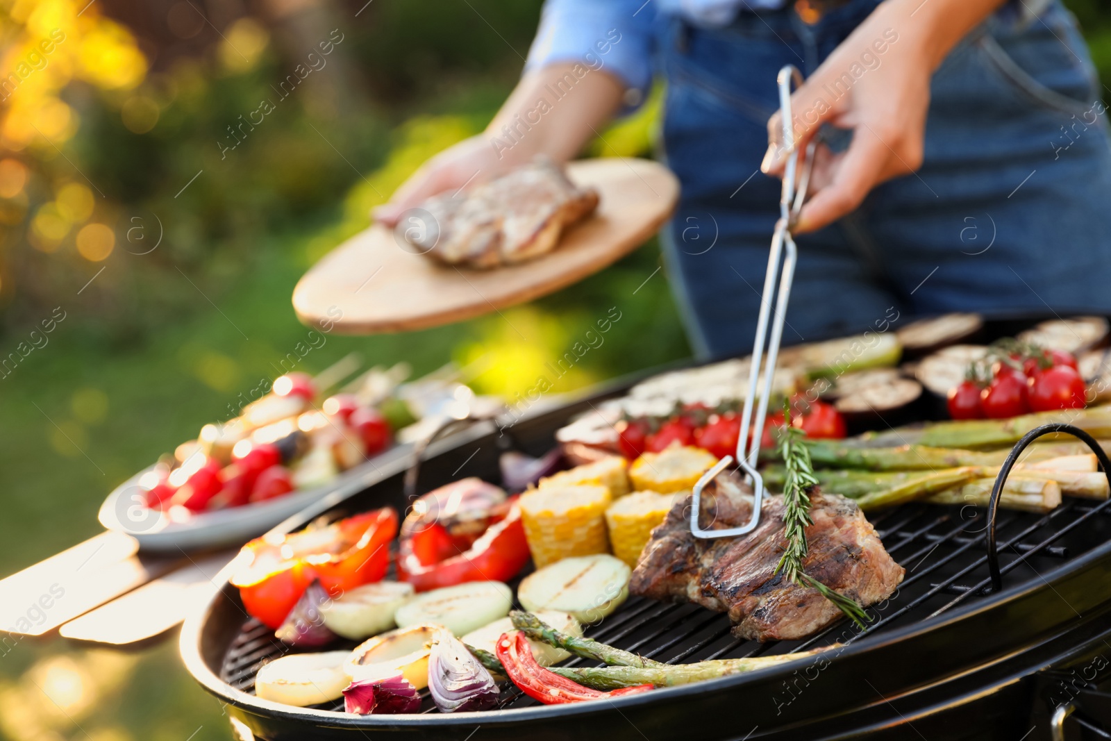 Photo of Woman cooking meat and vegetables on barbecue grill outdoors, closeup