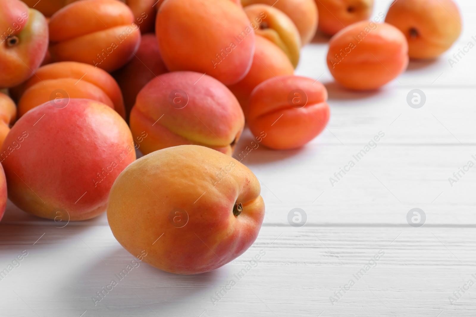 Photo of Delicious fresh ripe apricots on white wooden table