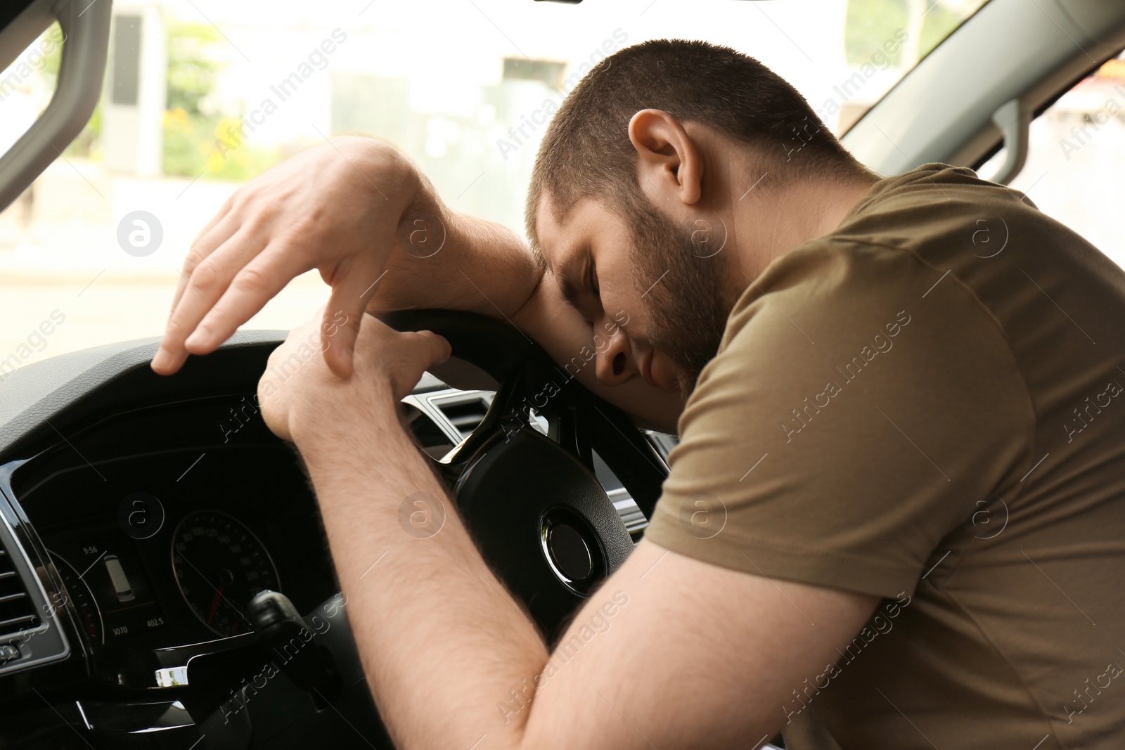 Photo of Tired man sleeping on steering wheel in his car