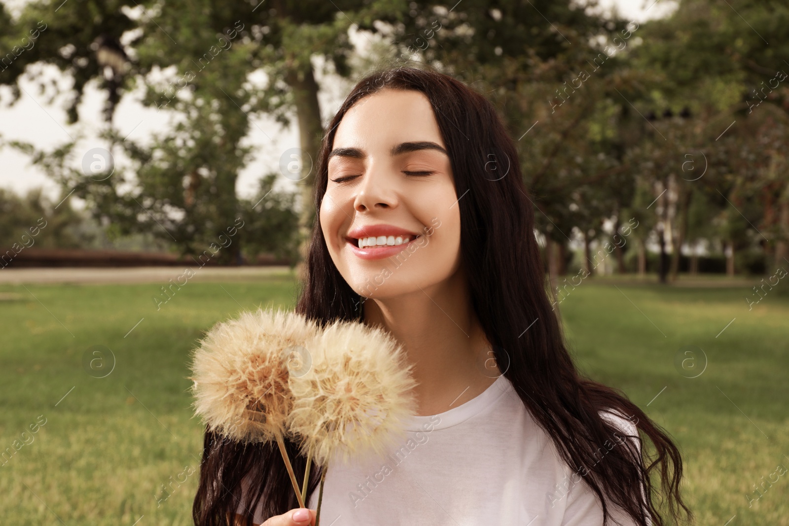 Photo of Beautiful young woman with large dandelions in park. Allergy free concept