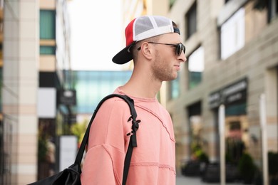 Photo of Handsome young man with stylish sunglasses and backpack on city street