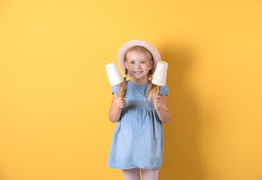 Cute little girl with cotton candies on color background