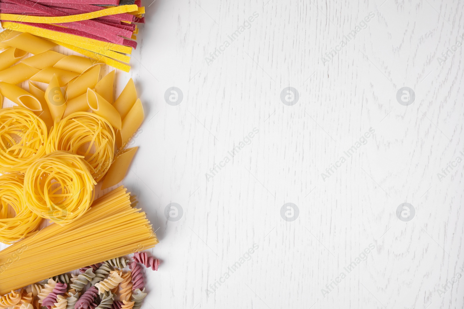 Photo of Different types of pasta on white wooden table, flat lay. Space for text