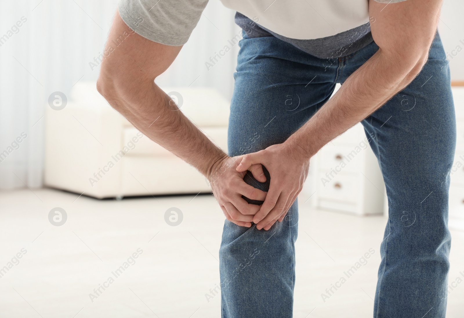 Photo of Young man suffering from leg pain indoors, closeup. Space for text