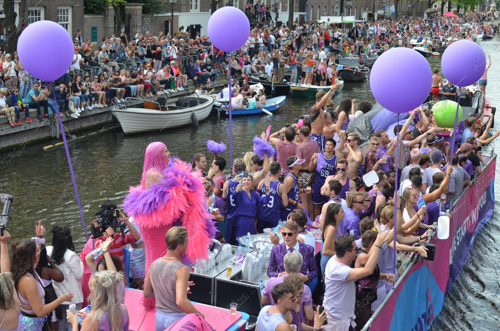 Photo of AMSTERDAM, NETHERLANDS - AUGUST 06, 2022: Many people in boats at LGBT pride parade on river