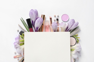 Photo of Makeup products, spring flowers and blank card on white background, top view. Space for text