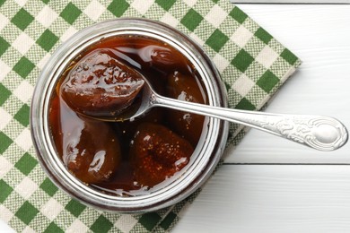 Jar of tasty sweet fig jam on white wooden table, top view