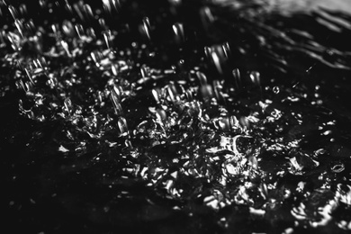 Photo of Heavy rain falling down on ground against dark background, closeup