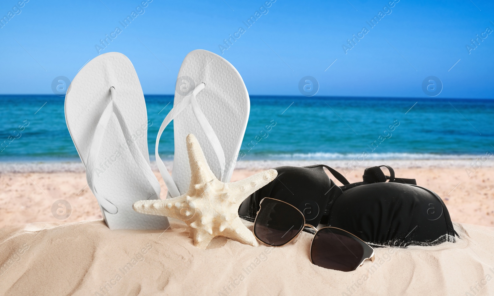 Image of Different beach accessories on sand near sea