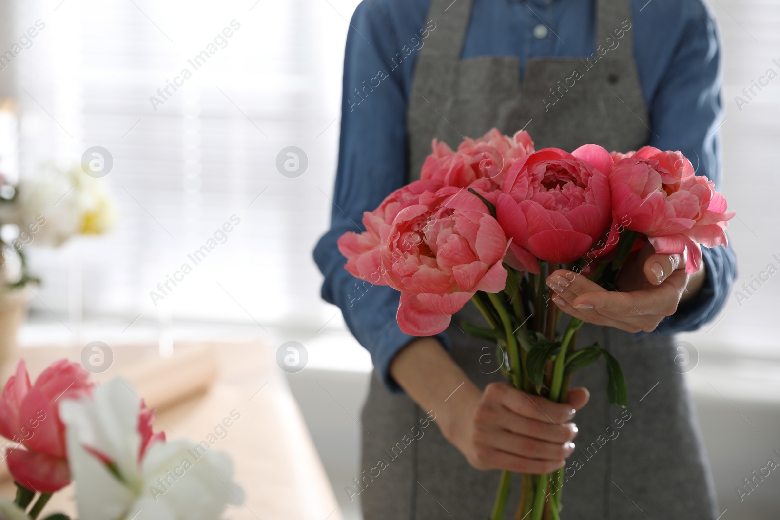 Photo of Florist with beautiful peony bouquet indoors, closeup