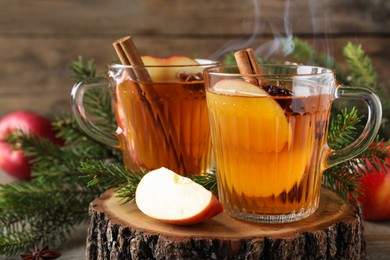 Photo of Hot mulled cider, ingredients and fir branches on wooden table