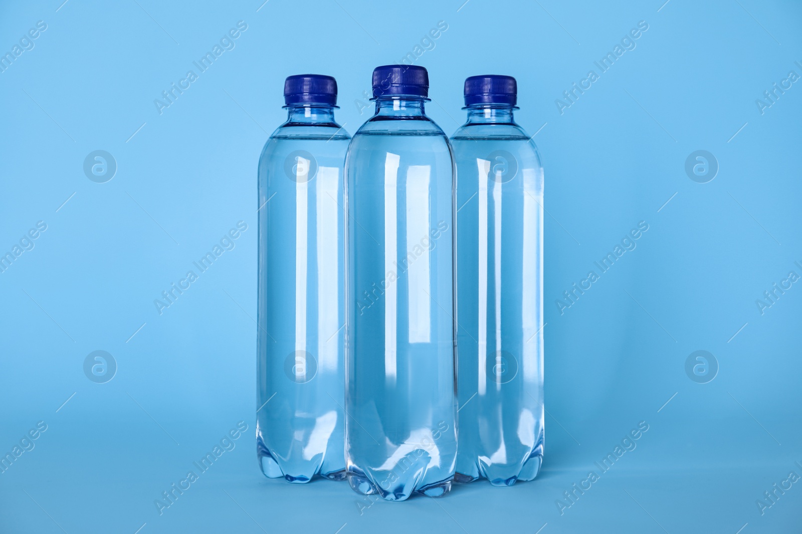 Photo of Plastic bottles with water on light blue background