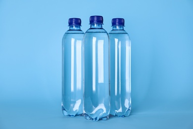 Photo of Plastic bottles with water on light blue background