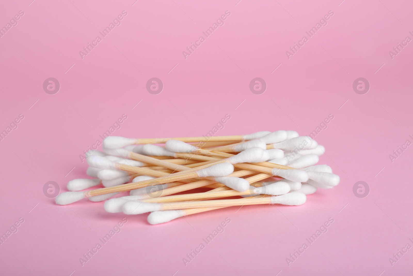 Photo of Many wooden cotton buds on pink background