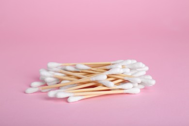 Many wooden cotton buds on pink background