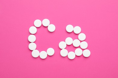 Photo of Calcium symbol made of white pills on pink background, flat lay