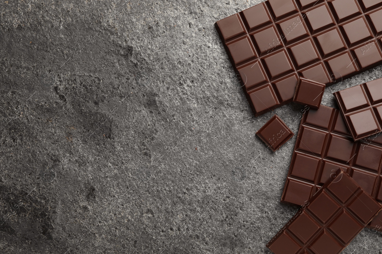 Photo of Delicious dark chocolate on grey table, flat lay. Space for text