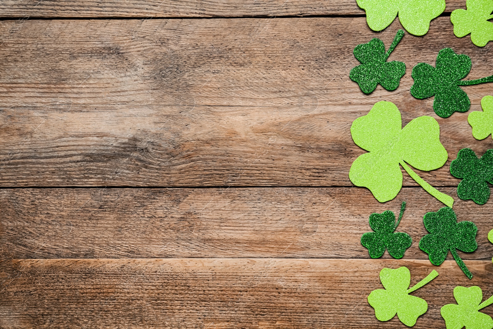 Photo of Decorative clover leaves on wooden table, flat lay with space for text. Saint Patrick's Day celebration