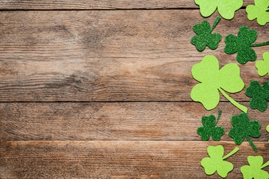 Decorative clover leaves on wooden table, flat lay with space for text. Saint Patrick's Day celebration