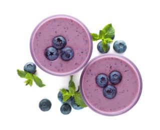 Glasses of blueberry smoothie with fresh berries and mint on white background, top view