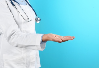 Photo of Female doctor offering helping hand on color background, closeup