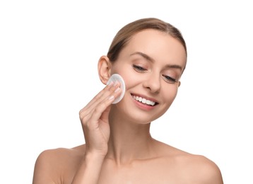 Smiling woman removing makeup with cotton pad on white background