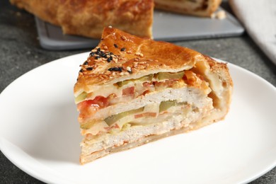 Photo of Piece of tasty homemade pie with filling served on grey table, closeup