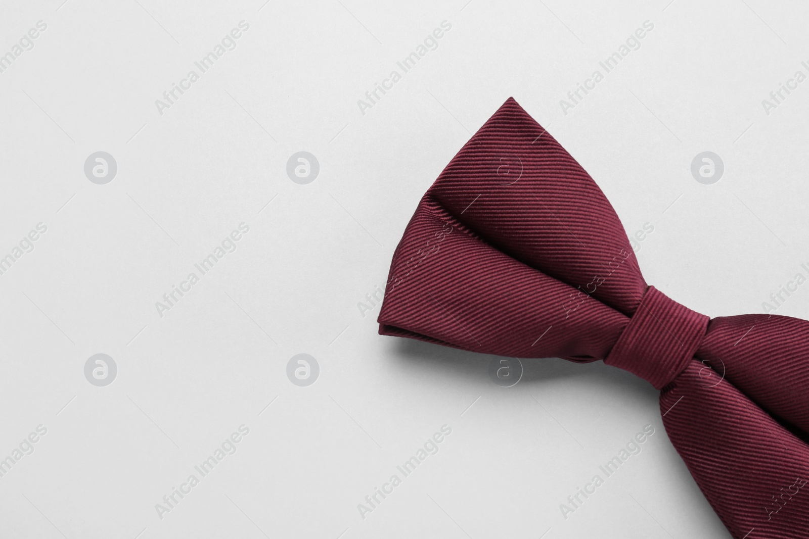 Photo of Stylish burgundy bow tie on white background, top view. Space for text