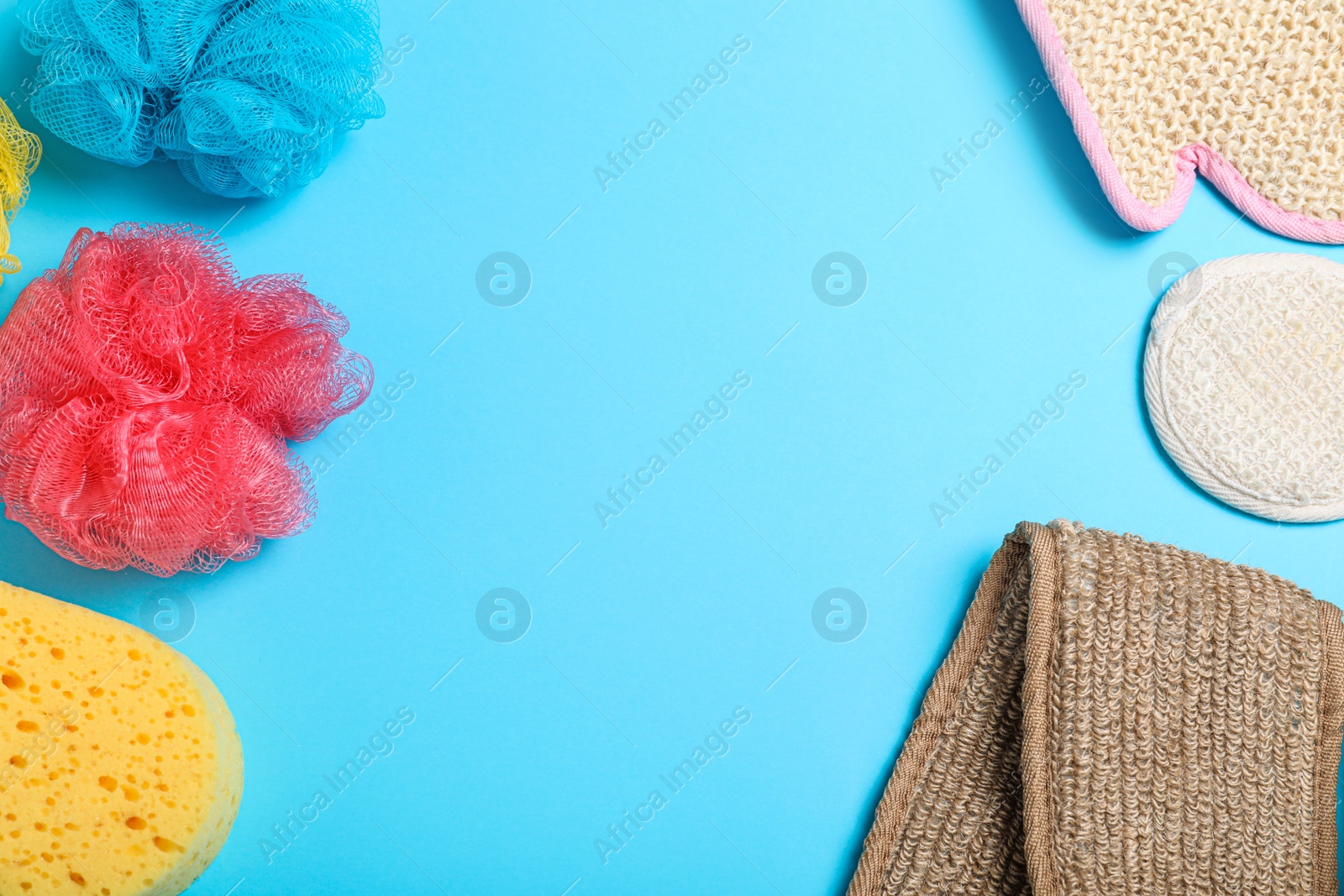 Photo of Flat lay composition with plastic and natural shower sponges on light blue background, space for text. Recycling concept