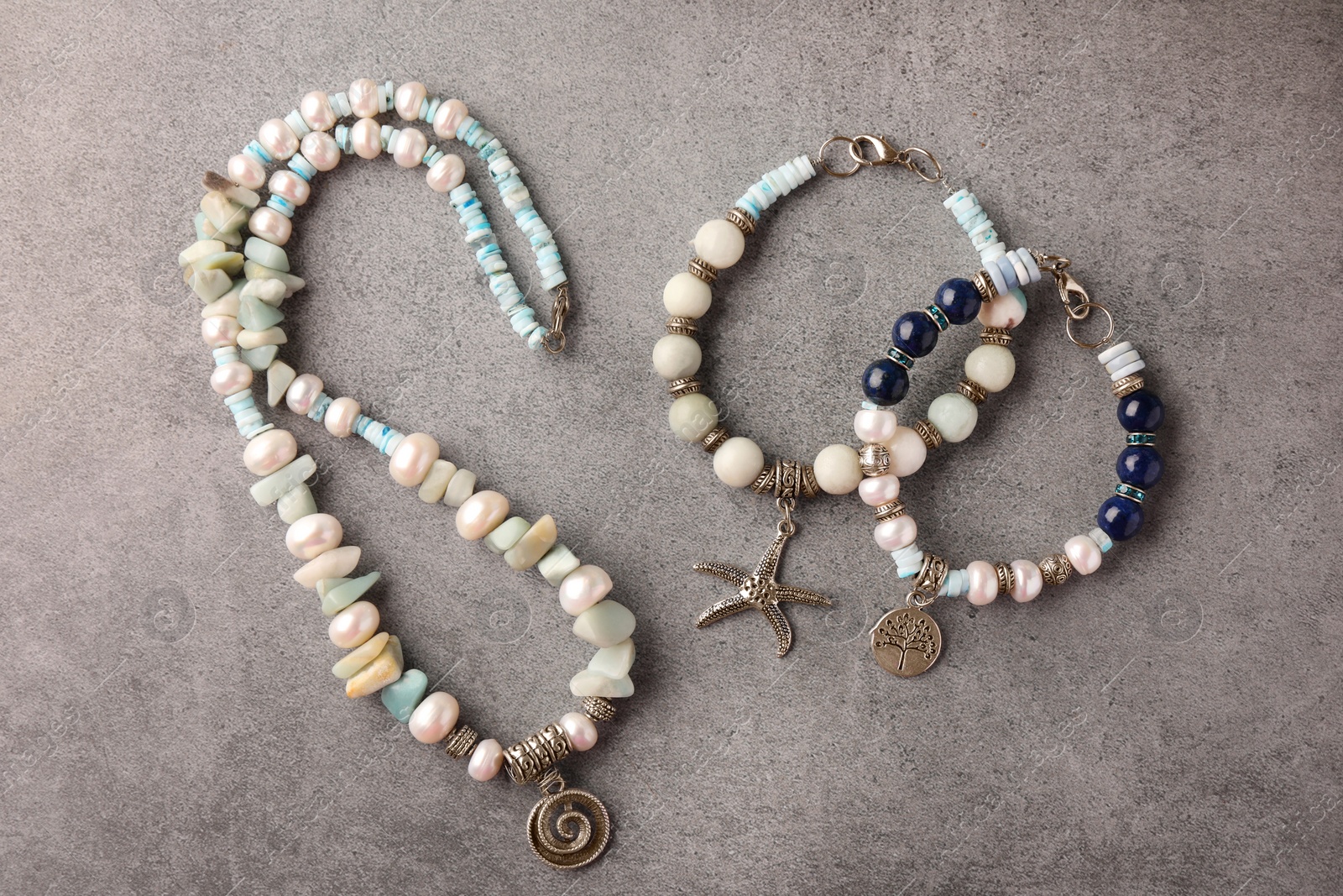 Photo of Different beautiful bracelets and necklace with gemstones on grey background, flat lay