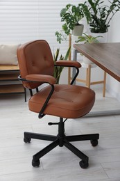 Photo of Stylish office interior with comfortable chair, desk and houseplants